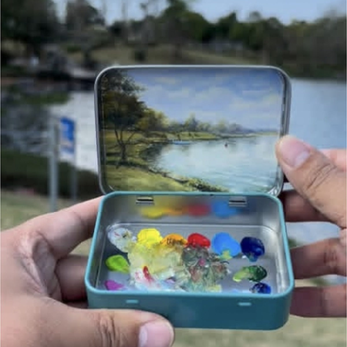 Custom travel memory pocket oil painting held open by a lake